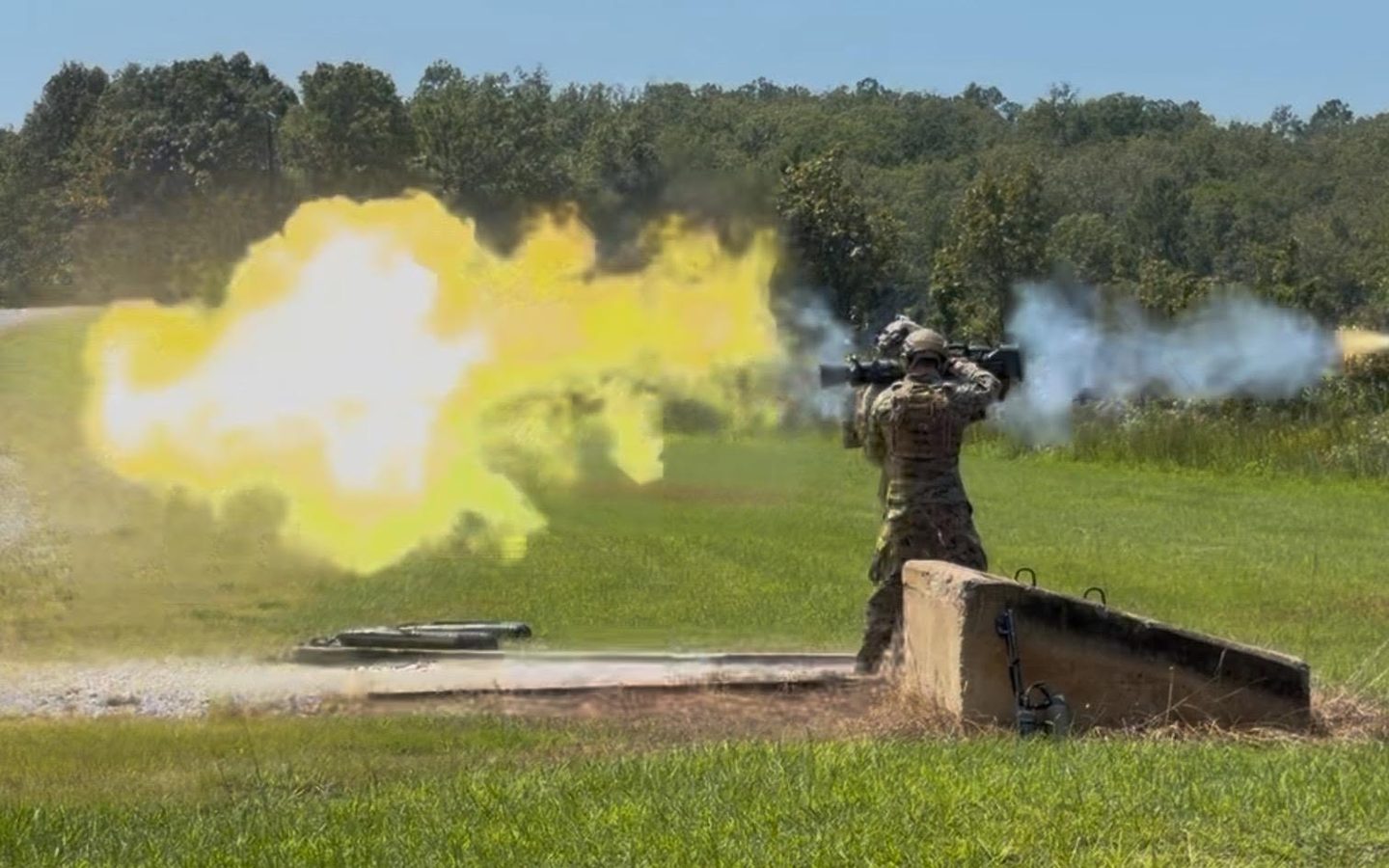 A rocket launcher fired on a range, a ball of flame and smoke beside the gunner