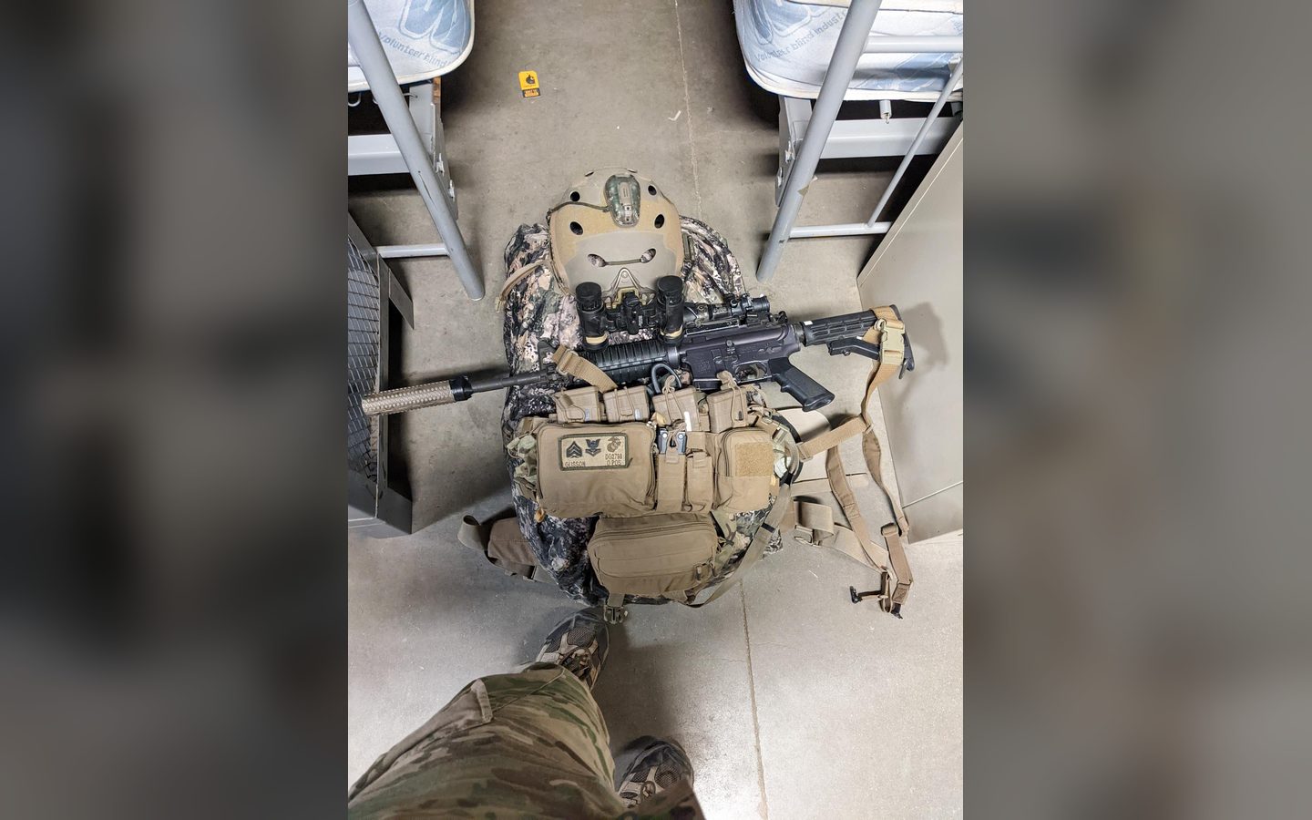 A full kit laid out on the floor: helmet, plate carrier, rifle