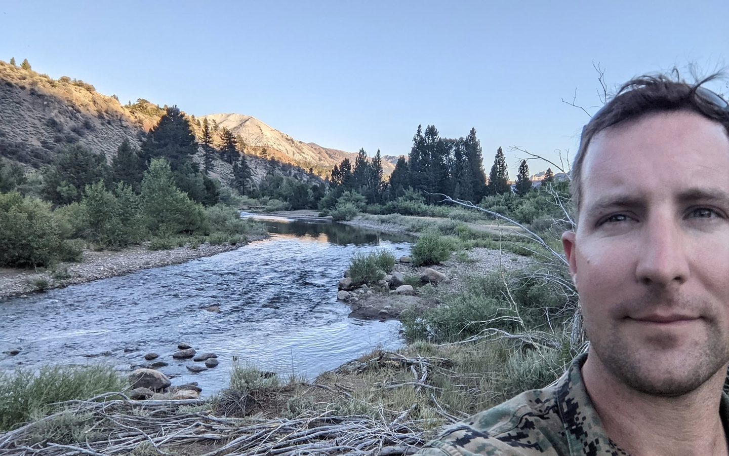 Daniel in the field beside a mountain river at first light