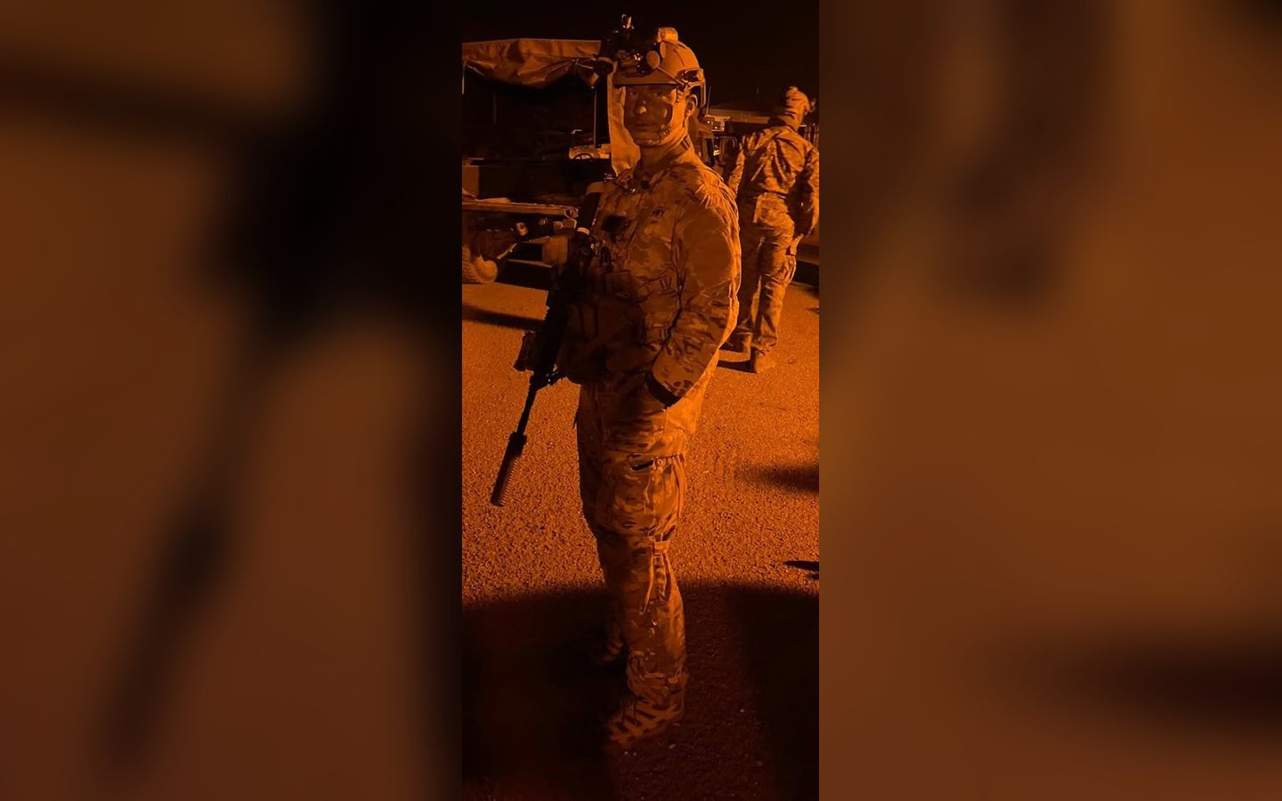 A Marine in full kit at night under orange lights