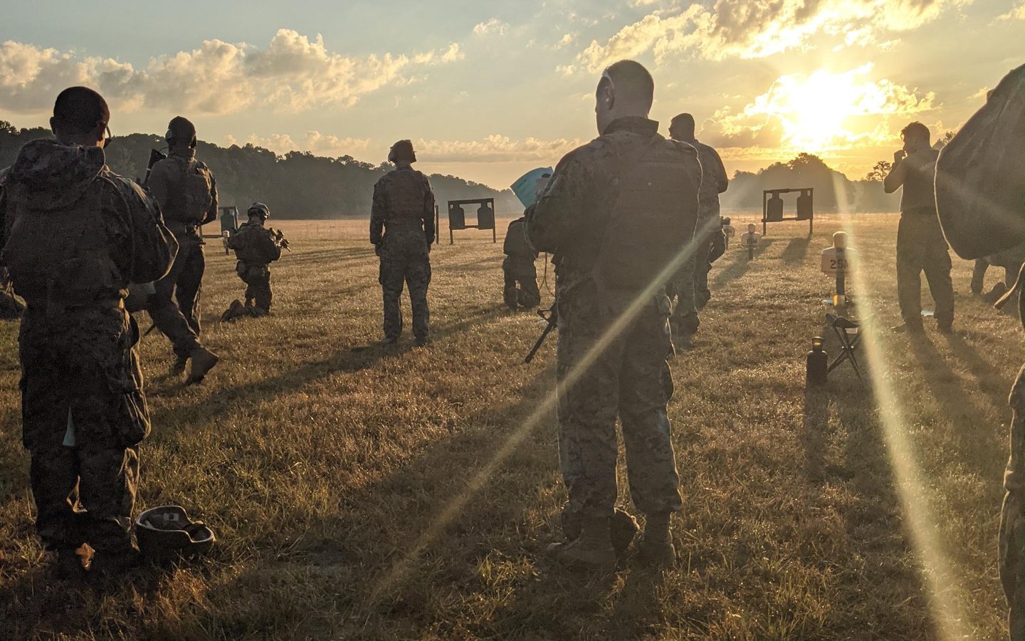Marines on a range at sunrise, long shadows across the grass
