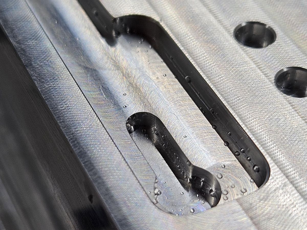 Close view of a milled slot and pocket in aluminum beside two chamfered holes